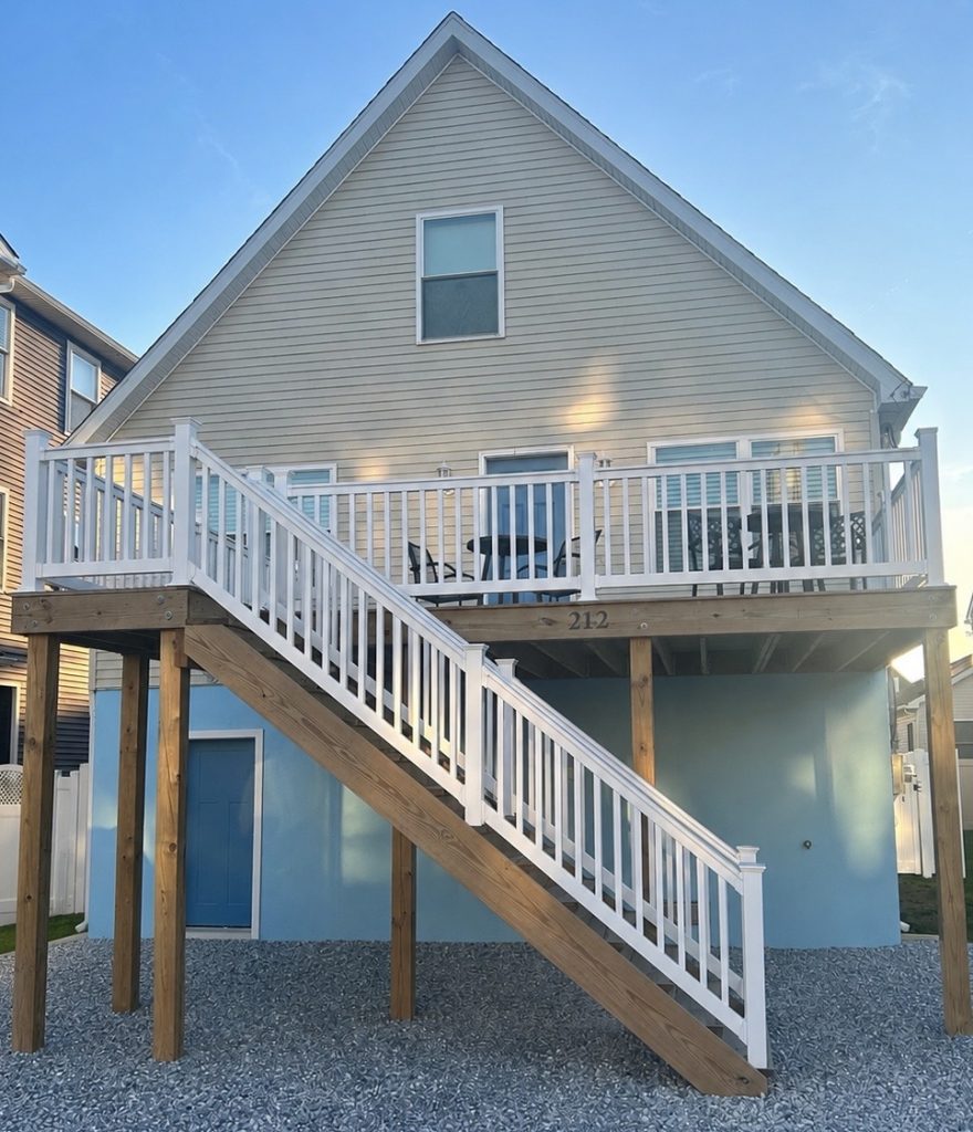 Exterior view of Brannan Shore, a raised beach house in Wildwood, New Jersey featuring an elevated deck, outdoor seating, private entrances and spacious outdoor area.
